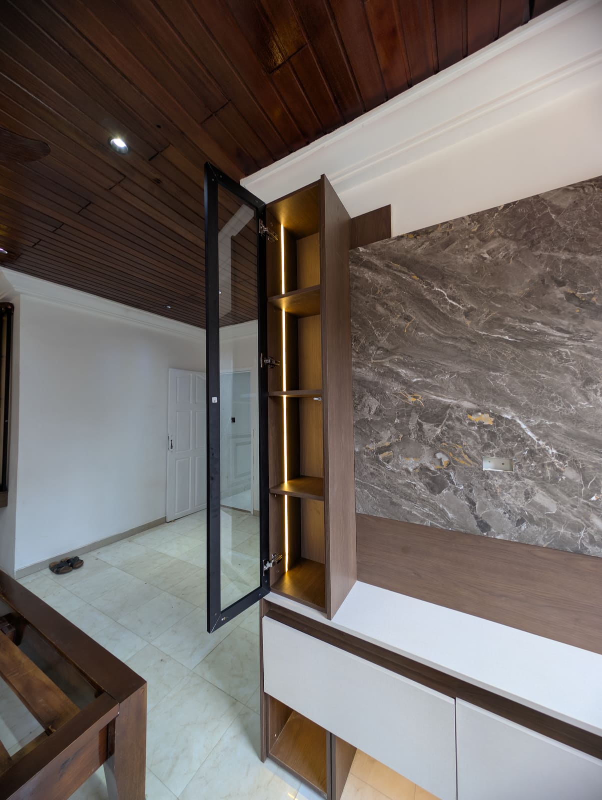 Open lit glass display cabinet against the marble feature wall