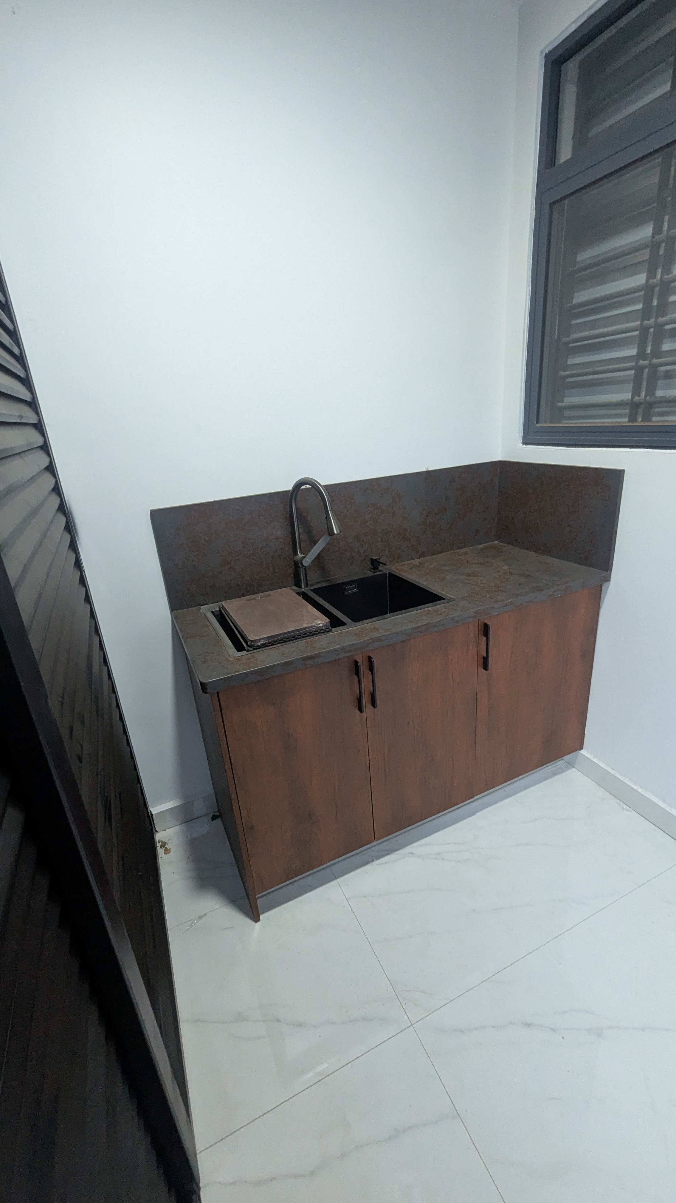 Compact kitchenette in warm russet laminate with dark stone-effect countertop — Dome, Accra