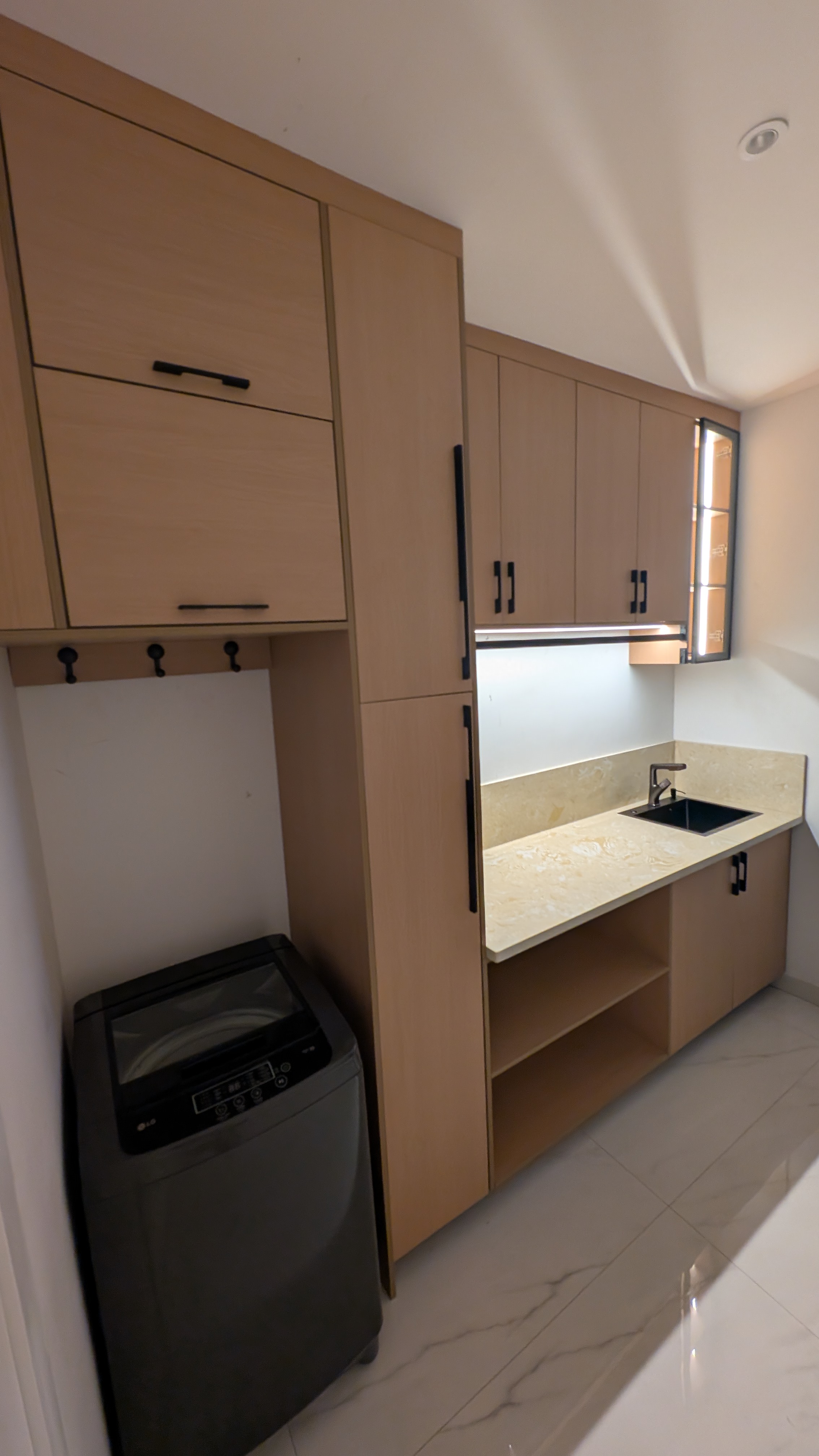 Compact kitchenette in warm russet laminate with dark stone-effect countertop — Dome, Accra