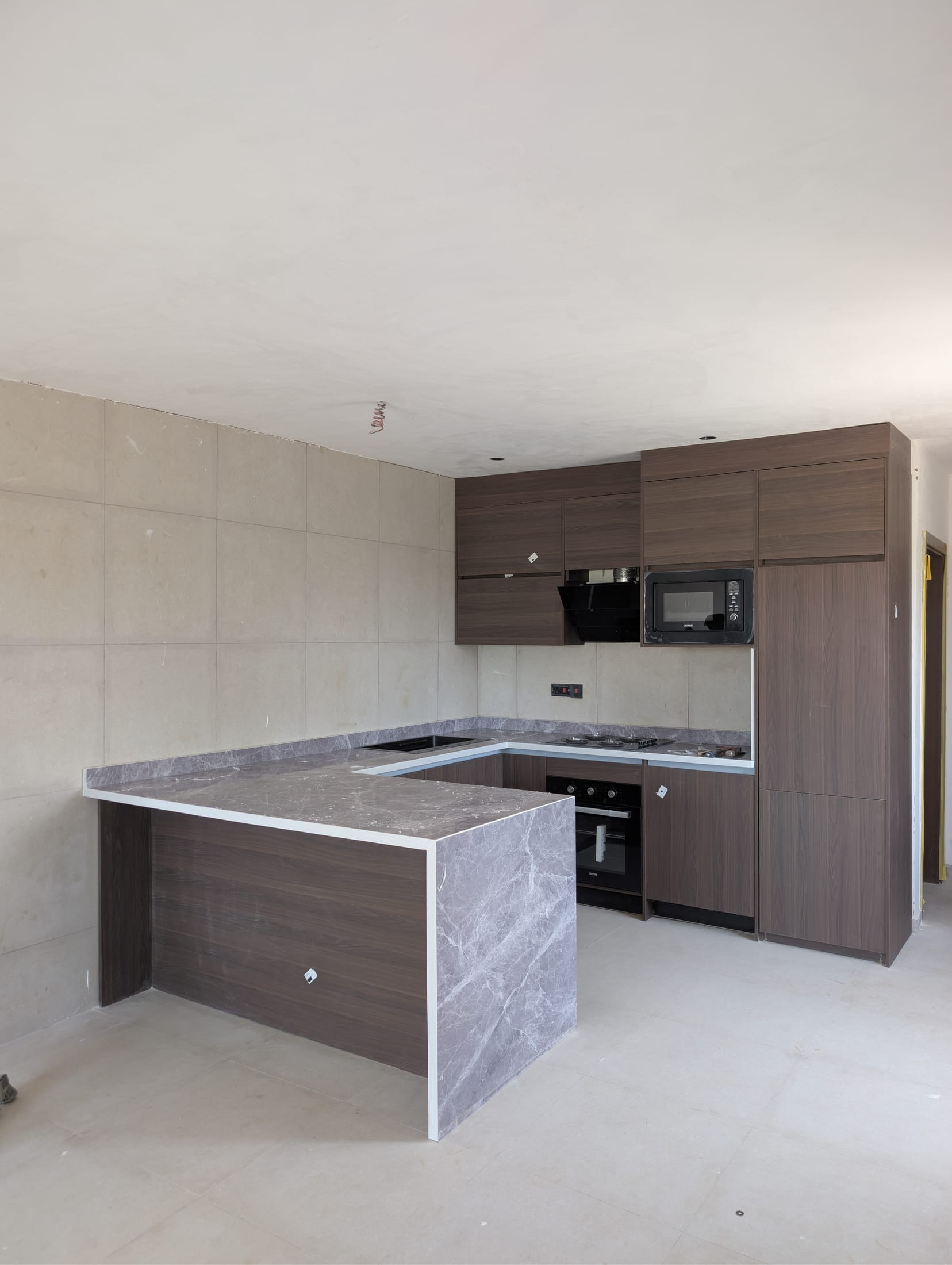 Open U-shaped kitchen with waterfall marble-effect peninsula, Prampram